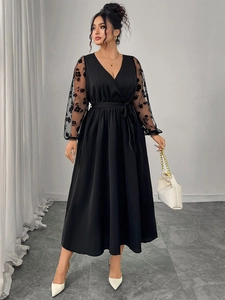 Detailed close-up of V-neckline and mesh sleeves with floral embroidery on black dress