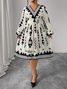 Close-up of V-neck dress with black tribal print and high waist pleated details