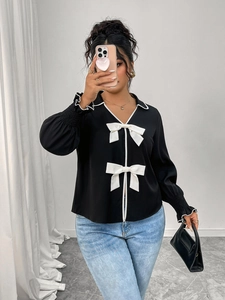 Detail of black polo collar jacket with white bows and contrast trim sleeves