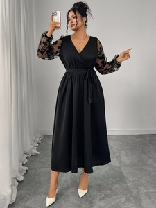 Detailed view of the black dress featuring sheer lace sleeves and intricate floral patterns
