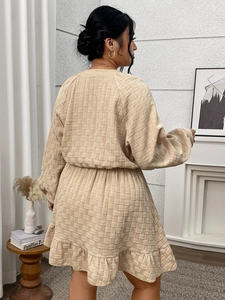 Détail de la robe trapèze beige texturée avec manches bouffantes et ourlet à volants