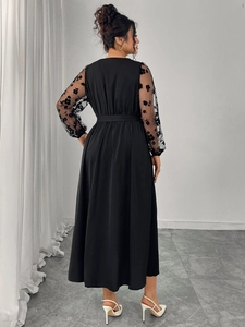 Detail of elegant black long dress showing floral mesh sleeves and cinched waistline
