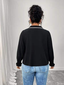 Back view of a black polo neck blouse with white contrast collar and ruffled cuffs