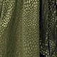 Close-up of dark green dress fabric featuring an elegant snakeskin scale texture
