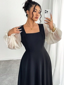 Détail du col carré et des manches bouffantes blanches sur cette robe noire ajustée