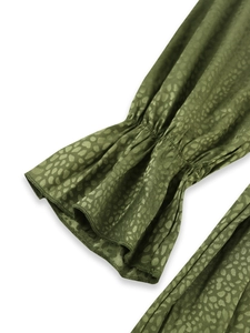 Detailed macro view of ruffle cuffs on an olive green dress with leopard print texture