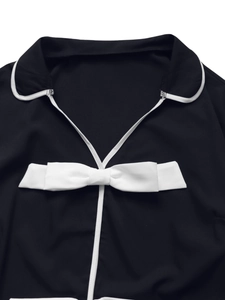 Detail of black polo collar jacket with white piping and a 3D bow accent