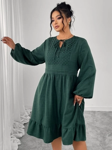 Détail de la robe vert foncé montrant les broderies ajourées et les manches bouffantes