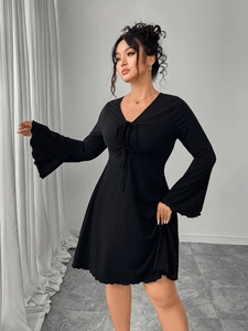 Detail view of deep V-neckline with adjustable drawstring on long sleeve black dress