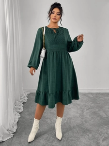 Détail d'une robe vert foncé avec broderie géométrique et lien à nouer au col