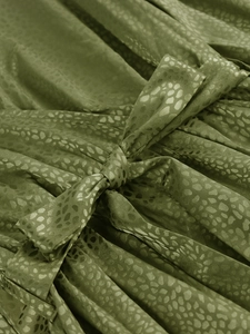 Detail of olive green satin dress featuring animal print pattern and elegant bow tie knot