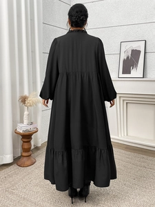 Detail of black tiered maxi dress with ruffled high neck and elegant long sleeves