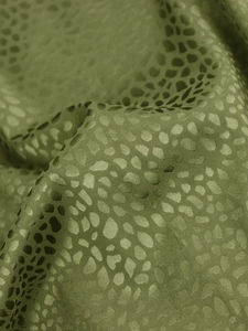 Detail of sage green satin fabric with leopard jacquard texture and silky sheen