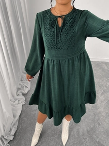 Détail d'une robe en coton vert foncé avec broderie carrée et manches bouffantes
