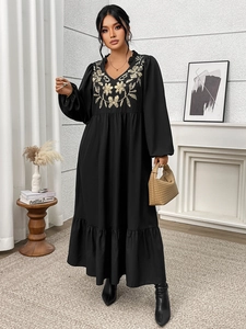 Detailed view of elegant gold floral embroidery on the V-neck of a black long maxi dress