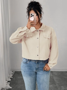 Detail view of cream corduroy jacket featuring silver metal buttons and flap pockets