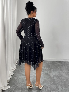 Detail of black chiffon dress featuring white bow patterns and asymmetric hem from back view