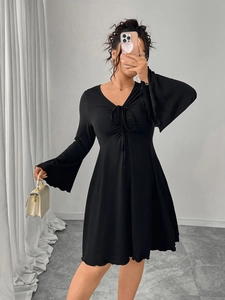 Detail of V-neck tie-front black dress with flared sleeves and ruched chest design