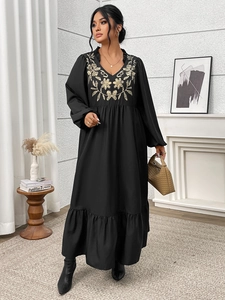 Detail of V-neckline with ruffles and golden floral embroidery on black maxi dress