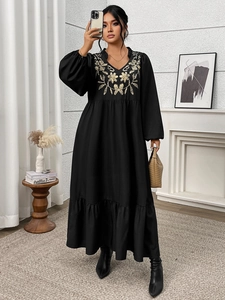 Detail of floral embroidery on a black V-neck dress with ruffle trim and lantern sleeves