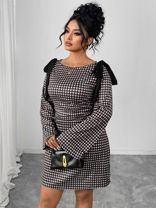 Detail shot of oversized black bows on the shoulders of a gingham long sleeve dress