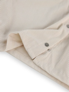 Close-up of beige corduroy fabric texture with metallic snap button and detailed stitching