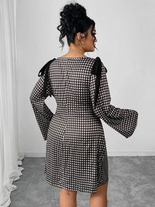Rear view of plaid long sleeve dress with black ribbon bows on shoulders and flared cuffs