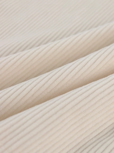 Macro view of cream corduroy jacket fabric showing soft ribbed texture and vertical lines
