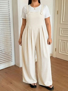 Detailed close-up of cream wide-leg overalls featuring V-shaped stitching and pleated texture