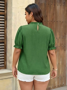 Detail of dark green textured blouse showing ruffled high collar and back teardrop cutout