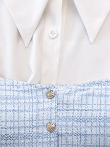 Detail of tweed dress fabric with gold buttons and white shirt collar ensemble