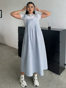 Detail of the blue striped overall dress with adjustable bow shoulder straps and white t-shirt