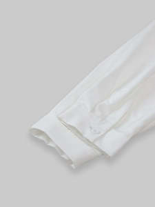 Close-up of white long-sleeved shirt cuff with round button and fine fabric texture