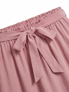 Detail of high waisted pink tiered skirt with elastic smocked waist and a matching bow tie