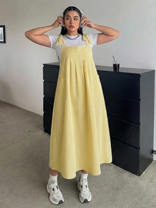 Detail of yellow striped overall dress featuring shoulder ties and large front pockets