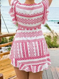 Back view of bohemian pink geometric print dress with ruffled hem at the beach