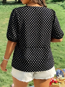 Outdoor view of summer navy polka dot blouse featuring puffy sleeves and hemline details