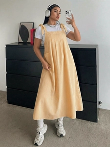 Detail of yellow and white striped midi dress showing bow tie straps and side pockets