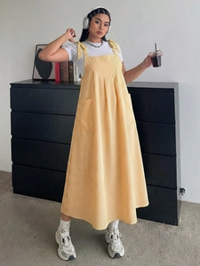 Detail view of yellow vertical striped sundress with knot straps and front patch pockets