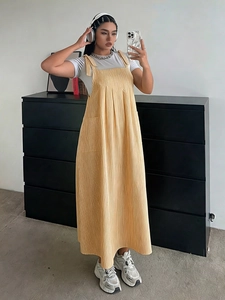 Detail of yellow corduroy overall dress showing loose fit and side pocket texture