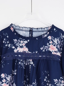 Détail d'une blouse en mousseline fleurie avec col à volants et empiècements en dentelle