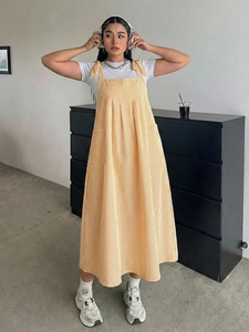 Detail of yellow striped pinafore dress with bow shoulder straps and front pockets
