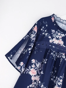 Détail d'une blouse en mousseline fleurie bleu marine avec col à volants et dentelle