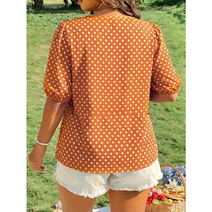 Women's summer orange polka dot blouse with puff sleeves and square neck on grass