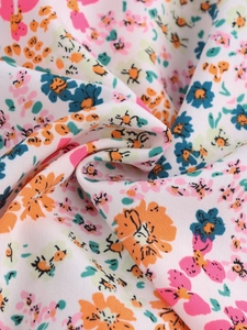Close-up of lightweight floral chiffon fabric with orange and pink blossom patterns