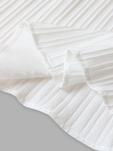 Detail of white pleated chiffon fabric showing soft vertical texture and lightweight material