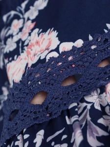 Détail du tissu en mousseline fleurie bleu foncé avec une bordure en dentelle crochetée