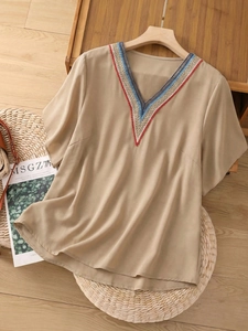 Détail de l'encolure en V avec broderie ethnique colorée sur chemisier beige