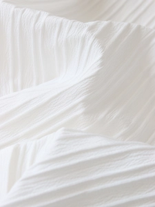 Detail of white pleated chiffon fabric showing exquisite accordion fold textures and light
