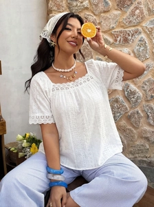 Detail of square neck white cotton top with eyelet embroidery and lace trim on the sleeves